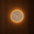 Månen travertine LED wall light glowing on a wood-panelled wall — NOGAN Lights