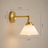 Vintage white glass wall light shown lit against a wall