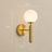 Gold designer wall light shown lit against a wall