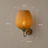 Natural bamboo wall light shown lit against a wall